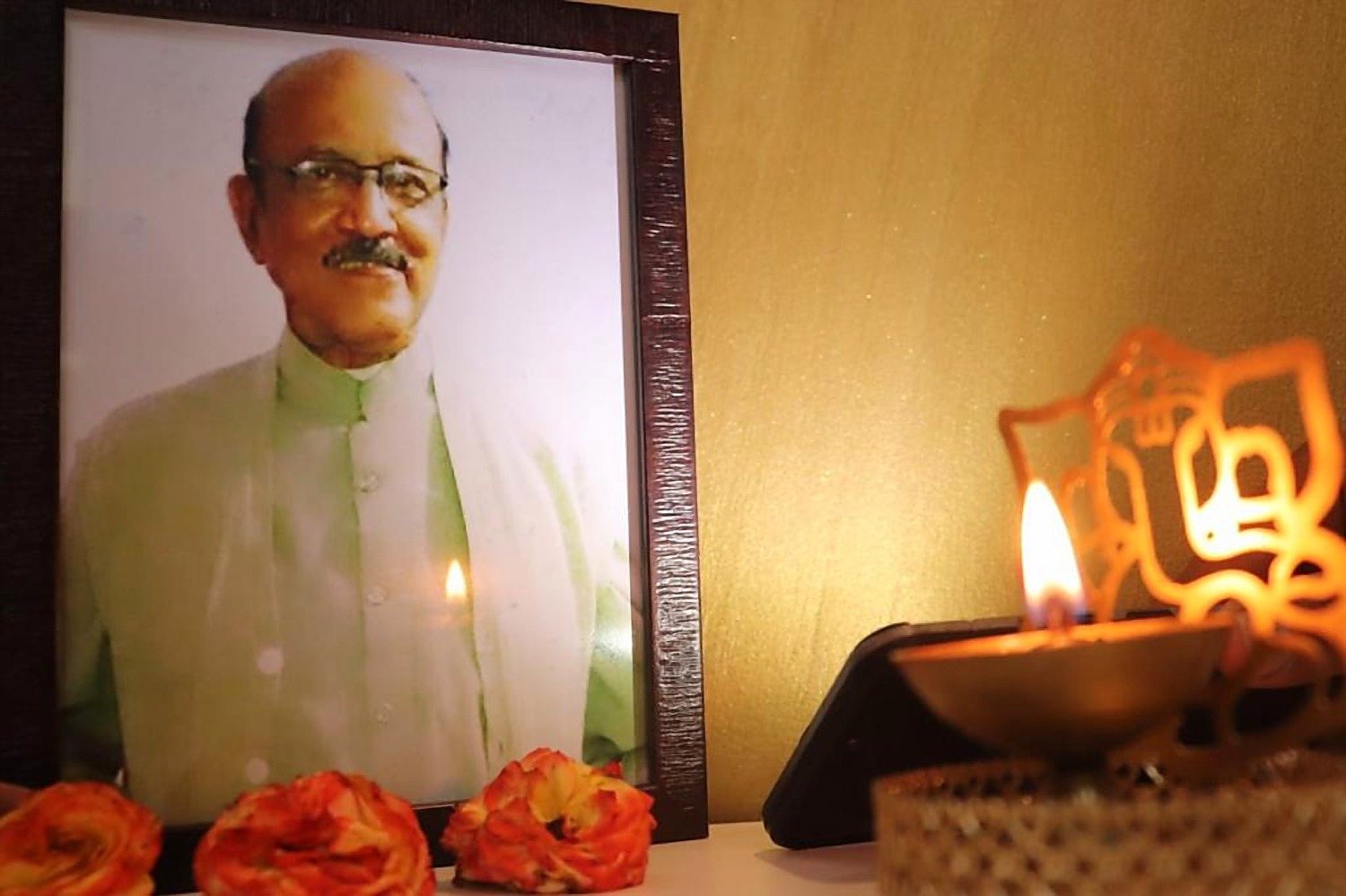 The framed portrait of the late Shri Ashok Das, kept in the clinic with a lamp and marigolds